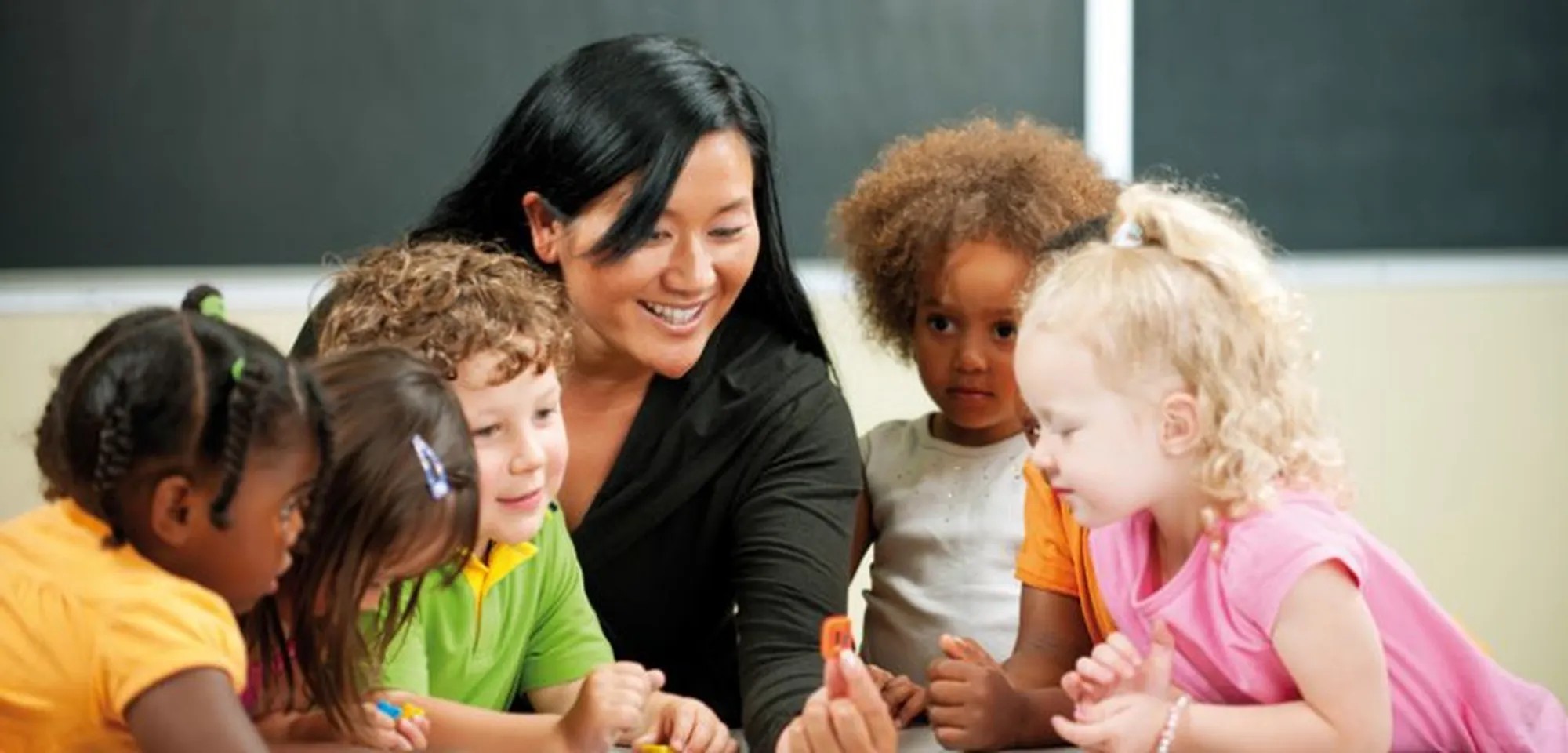 A woman is a seen with young children gathered around her at ylaa bilingual kindergarten, located in the iCITY Reinach building.